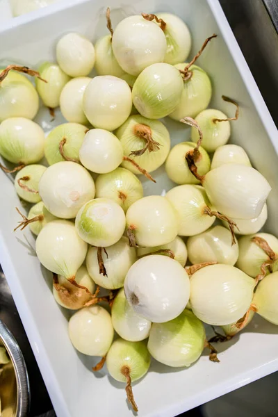 Bovenaanzicht van een wit dienblad met veel geschilde uien — Stockfoto