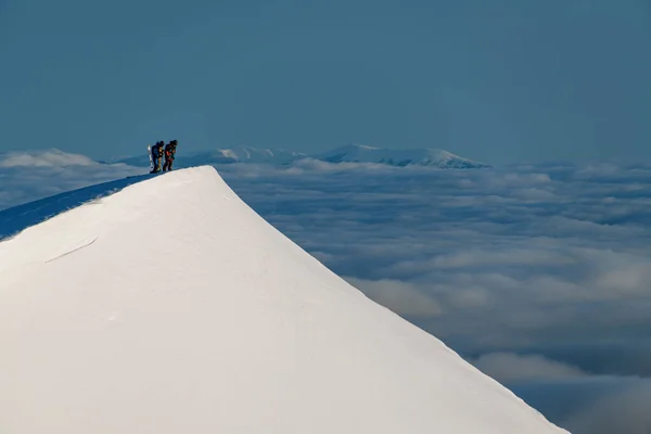 Wspaniały widok na szczyt przezroczystego białego śnieżnego zbocza góry z narciarzami na nim — Zdjęcie stockowe