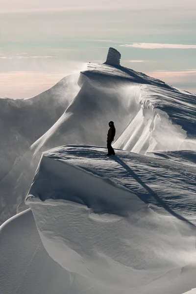 Beautiful view of a man standing on the top of a snow-covered mountain range — Stock Photo, Image