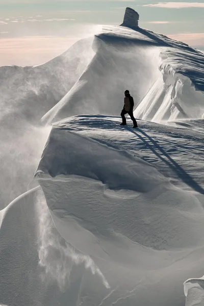 Wspaniały widok człowieka stojącego na szczycie pokrytego śniegiem pasma górskiego — Zdjęcie stockowe