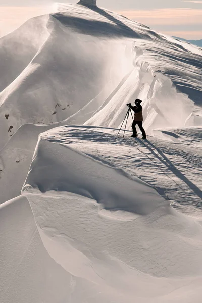 Dağın yamacında beyaz karla kaplı kameralı fotoğrafçı silueti.. — Stok fotoğraf