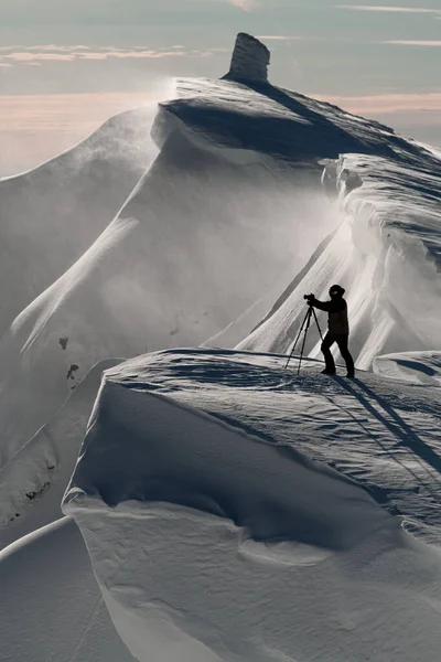 俯瞰着被白雪覆盖的山坡上的摄影师的轮廓. — 图库照片