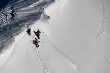 Karlı yamacın tepesine tırmanan freeriderların hava görüntüsü