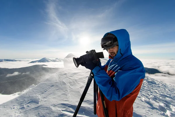 portrait of man with camera in his hands against a background of white snow and sky