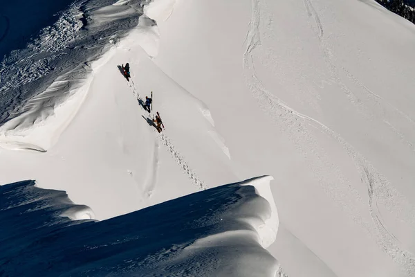 Awesome aerial view of the mountain range covered with powdery snow with people climbing on it — Zdjęcie stockowe
