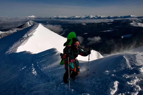 Man with ski equipment walks at trail on winter snowy mountain range — стоковое фото