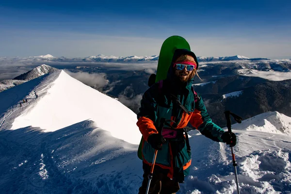 Man with ski equipment stands against the backdrop of beautiful winter mountain landscape — Fotografia de Stock