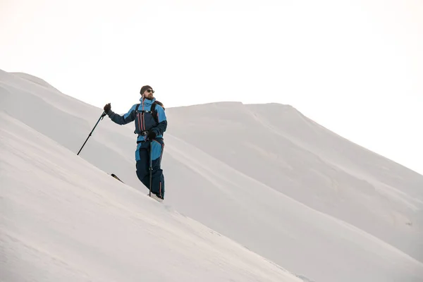 Άνθρωπος σκιέρ σε στέκεται και κοιτάζει προς τα πλάγια σε ένα φόντο του χιονιού — Φωτογραφία Αρχείου