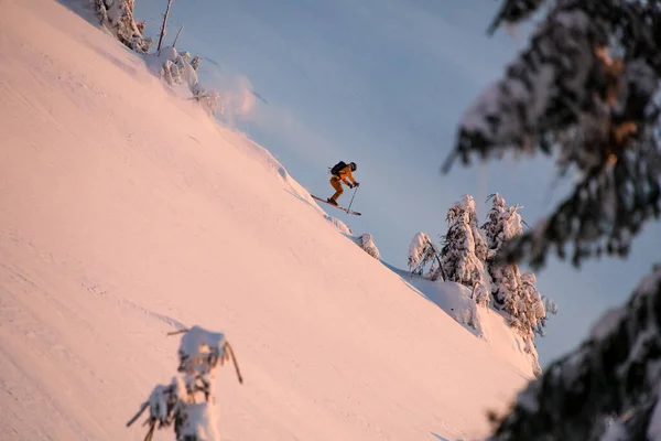 Great side view of jumping male skier at snowy mountain slope against backdrop of blue sky — Zdjęcie stockowe