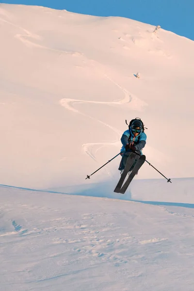 Фотография прыгающего лыжника на фоне снежного склона горы — стоковое фото