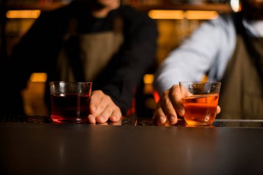 Bardakların güzel manzarası, barın üstünde parlak kokteyller ve erkeklerin elleri.