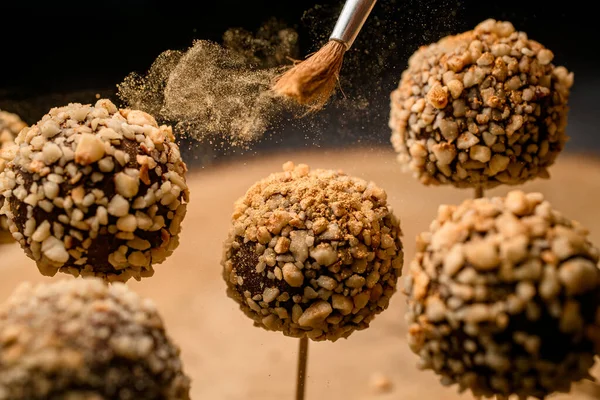 Close-up of chocolate candy pops on wood sticks which pour with powder — Stok Foto