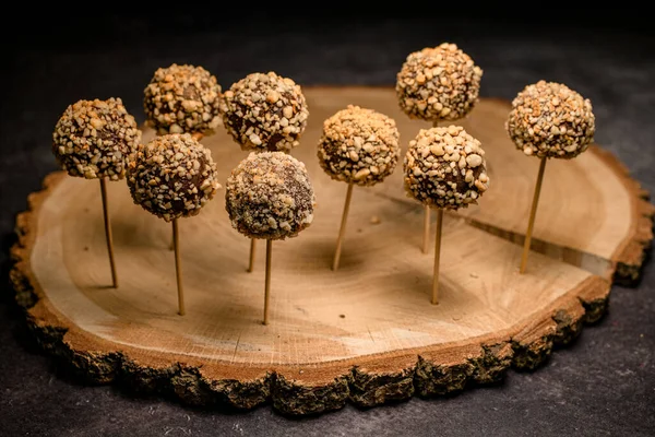 Pemandangan indah pada sekelompok permen coklat muncul pada tongkat di piring kayu — Stok Foto