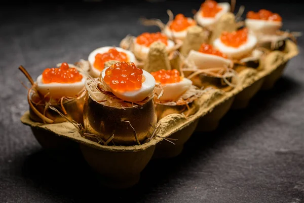 Selektivt fokus på läckra ägg fyllda med röd kaviar som serveras i gyllene skal i ägglåda — Stockfoto
