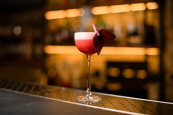 Cocktailglas met schuimige roze drank en decoratie op wazige bar achtergrond — Stockfoto