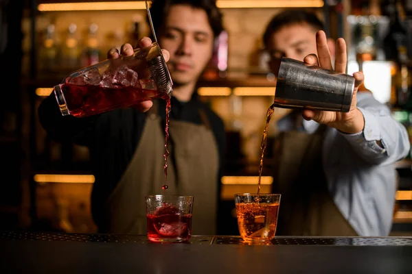 Два прозрачных стакана со льдом, в которых бармены тщательно залить различные коктейли — стоковое фото