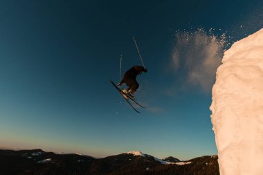 Mavi gökyüzünün arka planına karşı havada bir numara yapan serbest kayakçının harika manzarası.