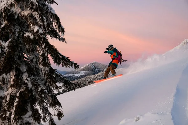 Homem freerider desliza por uma encosta nevada contra o pano de fundo de uma bela paisagem montanhosa — Fotografia de Stock