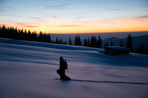 Belle vue de l'homme avec snowboard sur neige poudreuse profonde sur fond de coucher de soleil ciel et d'arbres — Photo