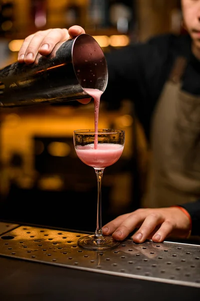 Бармен професійно п'є рожевий коктейль від шейкера в склянку — стокове фото