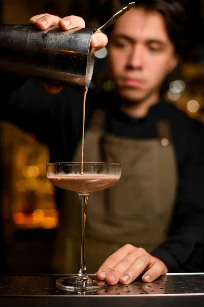 Бармен професійно п'є коричневий коктейль від шейкера в склянку — стокове фото