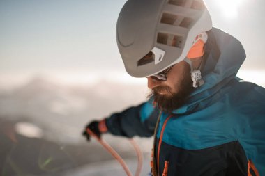 Güneş gözlüklü ve kayak kasklı sakallı adamın yakın plan görüntüsü.