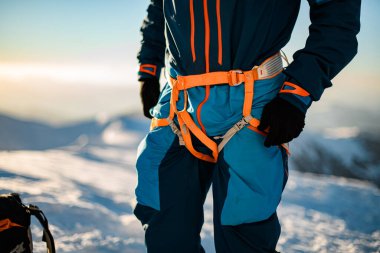 Kayakçıya takılan parlak turuncu tırmanma takımının yakın çekimi.