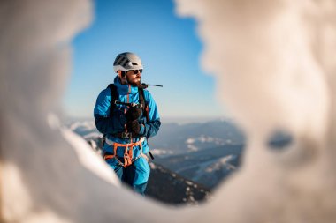 Mavi gökyüzünün zemininde kayak ekipmanı takan bir adamın portresi