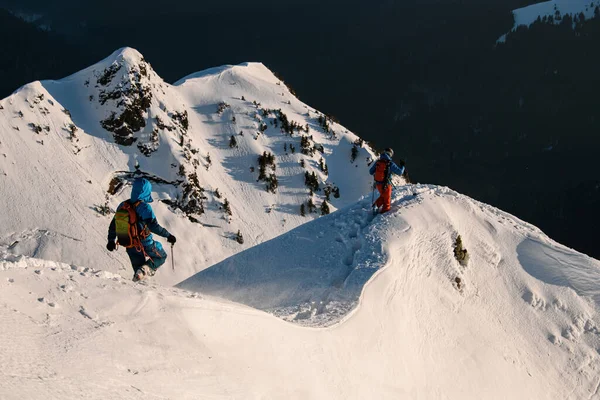 Turyści spacerują po zimowych górach na tle śnieżnych, surowych skalistych gór. Turystyka narciarska i koncepcja freeride — Zdjęcie stockowe