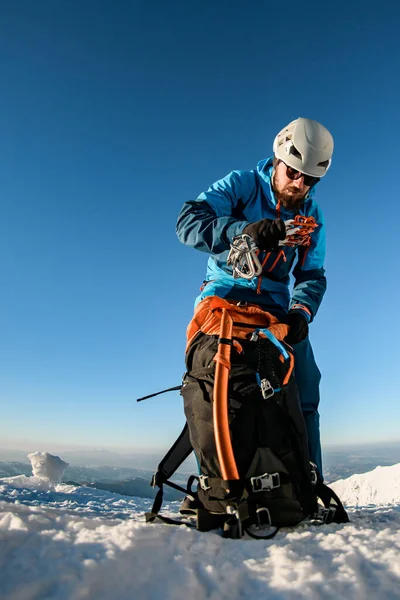 スキースーツの男とヘルメットは大きなバックパックにクライミング機器を入れて — ストック写真