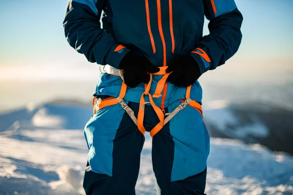 Крупный план ярко-оранжевого альпинистского снаряжения, надетого на лыжника. — стоковое фото