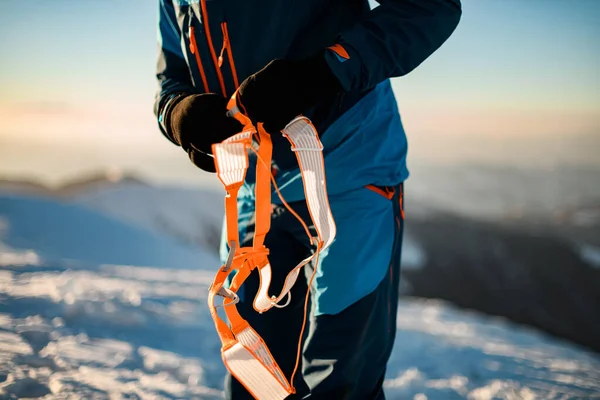 Close-up de equipamento de escalada laranja brilhante nas mãos de um homem — Fotografia de Stock