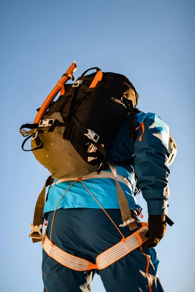 Visão traseira do corpo de um homem de terno de esqui com arnês de escalada e mochila. — Fotografia de Stock