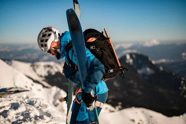 Вид сбоку человека с лыжами на фоне красивого зимнего горного пейзажа — стоковое фото