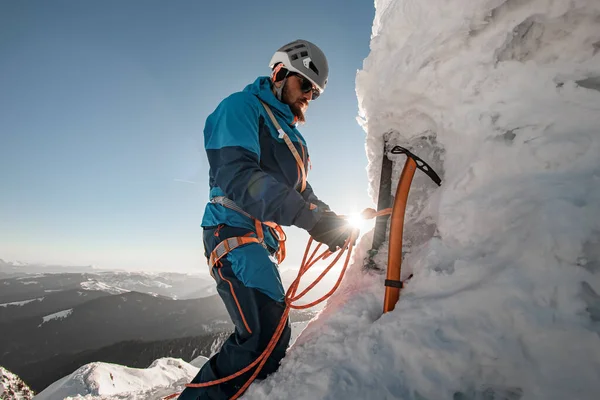 Pohled na ledovou sekeru a horolezce s vybavením a lany na svahu na pozadí oblohy — Stock fotografie