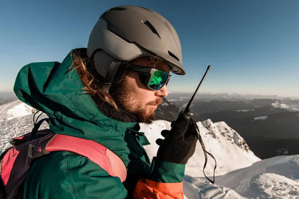 Πλευρική άποψη για το κεφάλι του ανθρώπου στο κράνος σκι με walkie-talkie στο χέρι του — Φωτογραφία Αρχείου