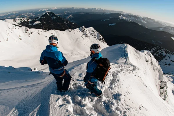 Visão traseira dos esquiadores na montanha coberta de neve contra o pano de fundo de uma bela paisagem — Fotografia de Stock