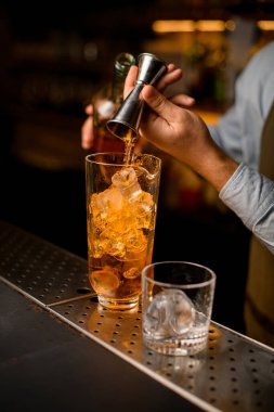 Barmenin eli Jigger 'dan içeceği nazikçe buzla karıştırır.