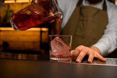 Bardakla süzgecin karışımından dökülen buzlu bardağın ön görüntüsü.