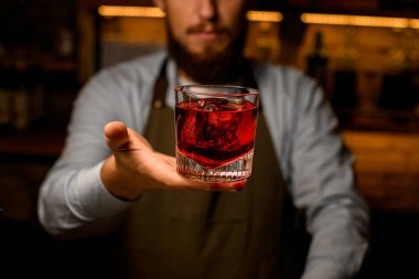 Parlak bir içecekle harika bir cam manzarası. Erkek bir barmenin nazikçe tuttuğu el.