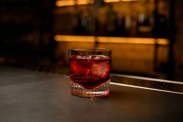 Great view of old-fashioned glass with a bright red cold beverage stands on bar — Stock Photo, Image