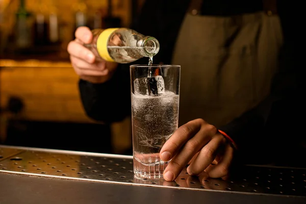 Zbliżenie szkła z zimnym napojem i kostkami lodu, w które barman dokładny wlewa napój z butelki — Zdjęcie stockowe