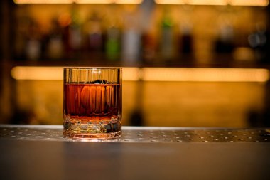 Alkollü içki ve bulanık arka planda bir parça buzla eski moda cam manzarası.