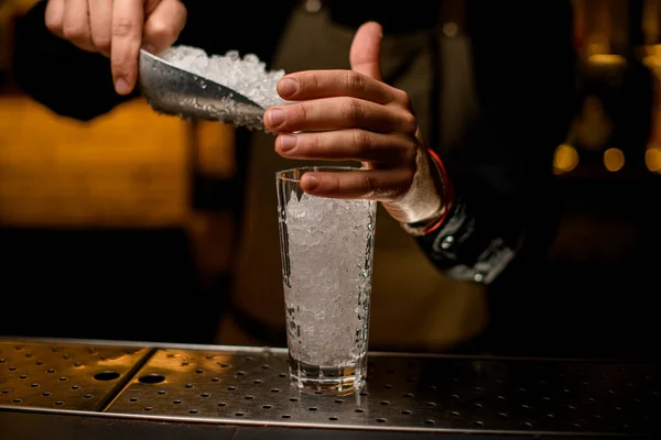 Mužská ruka blízko vysokého průhledného skla plného kusů ledu — Stock fotografie