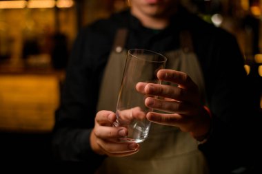 İçmek için şeffaf boş bir bardağı nazikçe tutan adamın elleri.