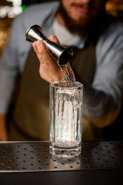 Bir jiggerdan sıvı dökülen buz küpleri ile cama bak