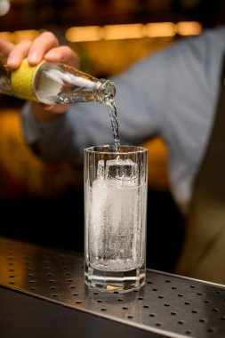 Şişeden tonik dökülen buzlu bardağa bak.