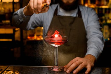 Bar tezgahında buzlu parlak şarap bardağı ve içki. Ve erkek eli nazikçe üzerine serpiştirir.