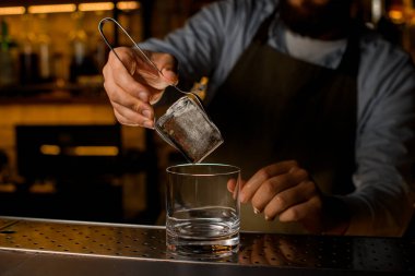 Büyük buz küpünün güzel manzarası erkeklerin elinde şeffaf camların üzerinde maşayla tutulur.