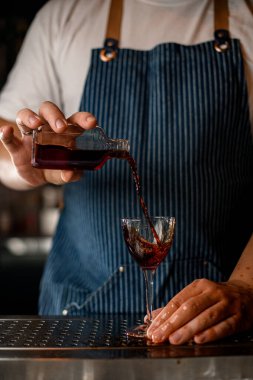 Erkek eli alkollü bir içecekle şişeyi tutuyor ve şarap bardağına döküyor.